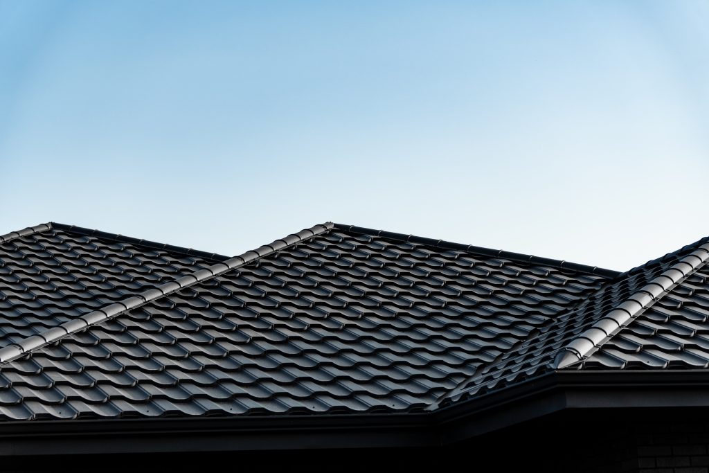 un toit avec des tuiles noirs devant un ciel bleu